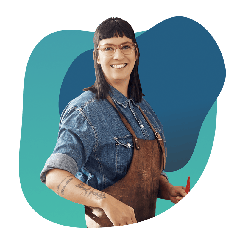 A smiling woman in a denim shirt and apron, representing business support and financial solutions.