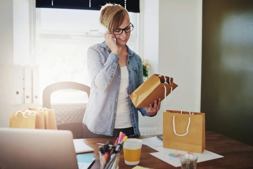 Woman packaging orders at home, small business owner working from home.