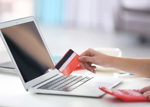 small businesses financial challenges Person making online payment with credit card on laptop.
