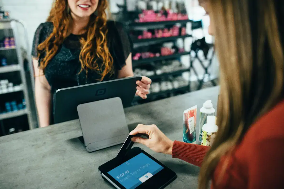 Customer using digital payment device at a retail counter.