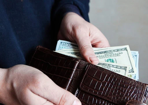 small businesses financial challenges Cash money in a brown leather wallet with US dollar bills.