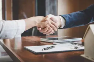 Business owner shaking hands with a direct business lender after reviewing financing documents