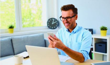 Man using smartphone with laptop, representing unsecured business loans.