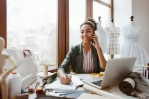 Small business owner working at a laptop and speaking on the phone in a clothing studio